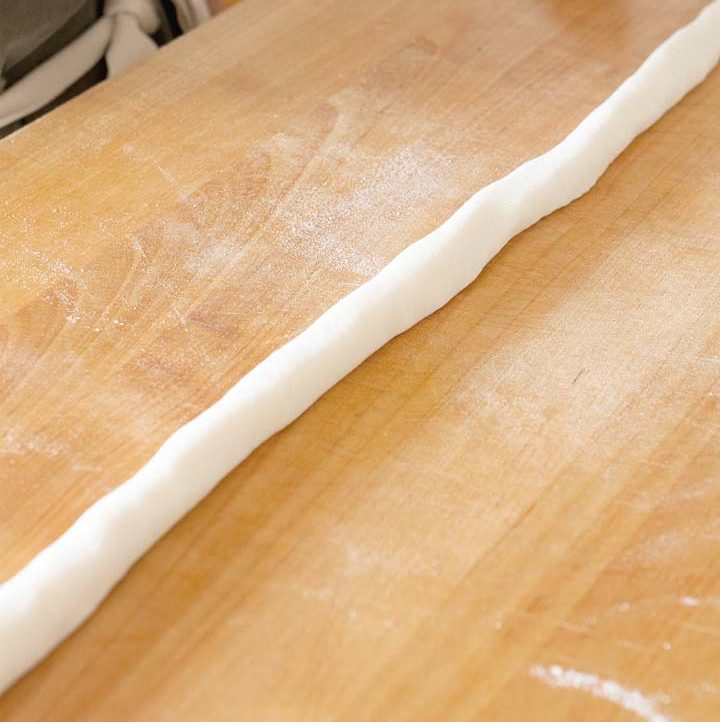 sweet rice dough rolled out into a long log shape on a wood cutting board