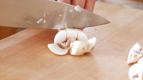 Diced white button mushroom on a wood cutting board.