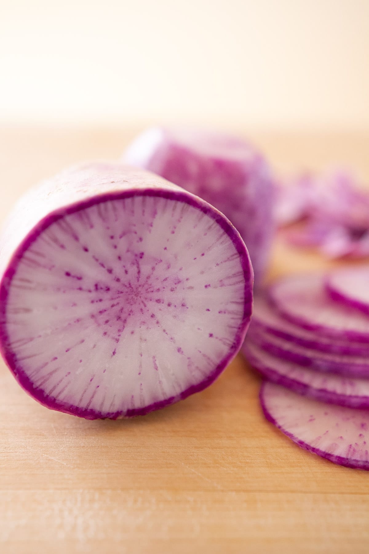 Sliced purple daikon on a wood cutting board to show the color and pattern of the insides.